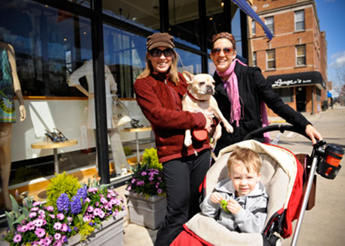 Two women, one holding a dog and the other a stroller with a child